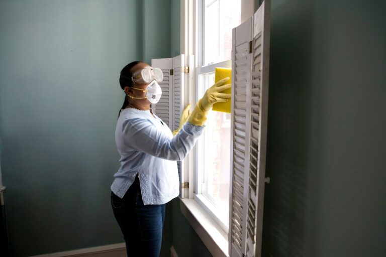 Persona limpiando una ventana para mantener el hogar ventilado y sin malos olores